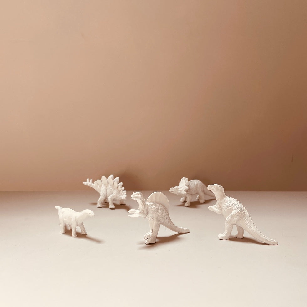 cinq-décorations-dinosaures-blancs-différents-sur-table blanche