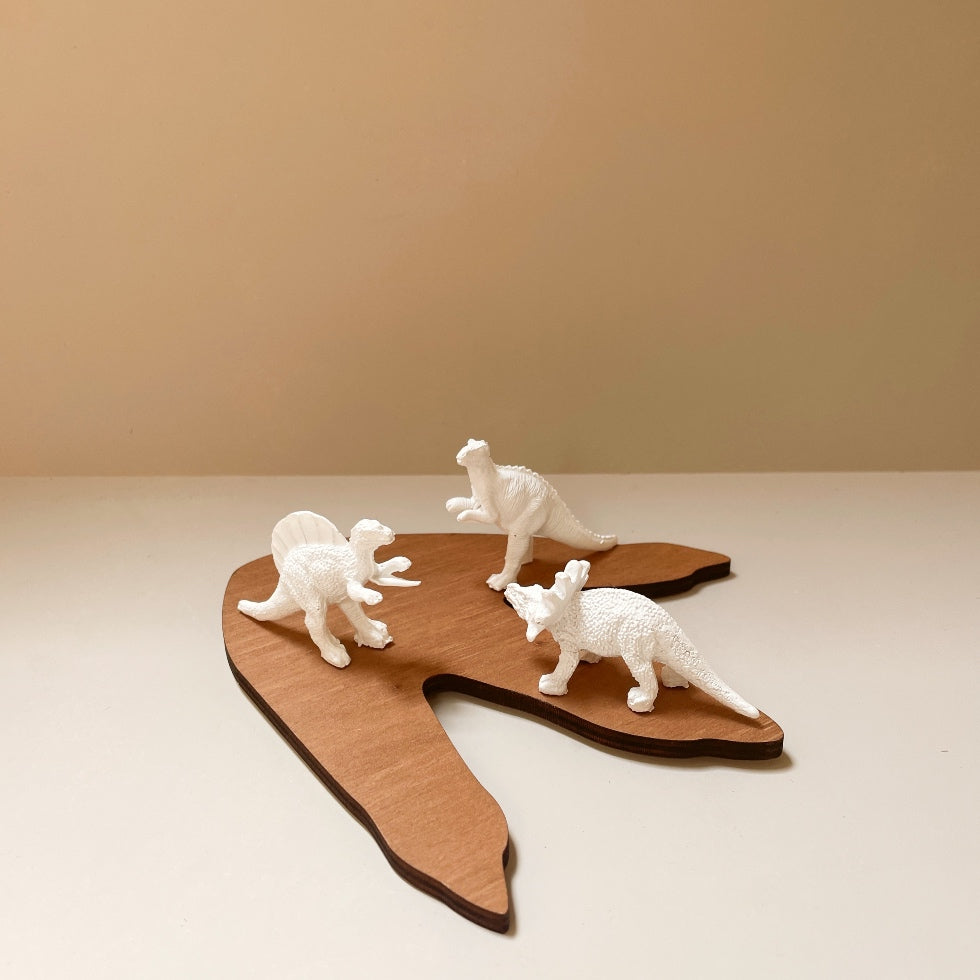3-figurines-dinosaures-blanches-sur-1-empreinte-bois